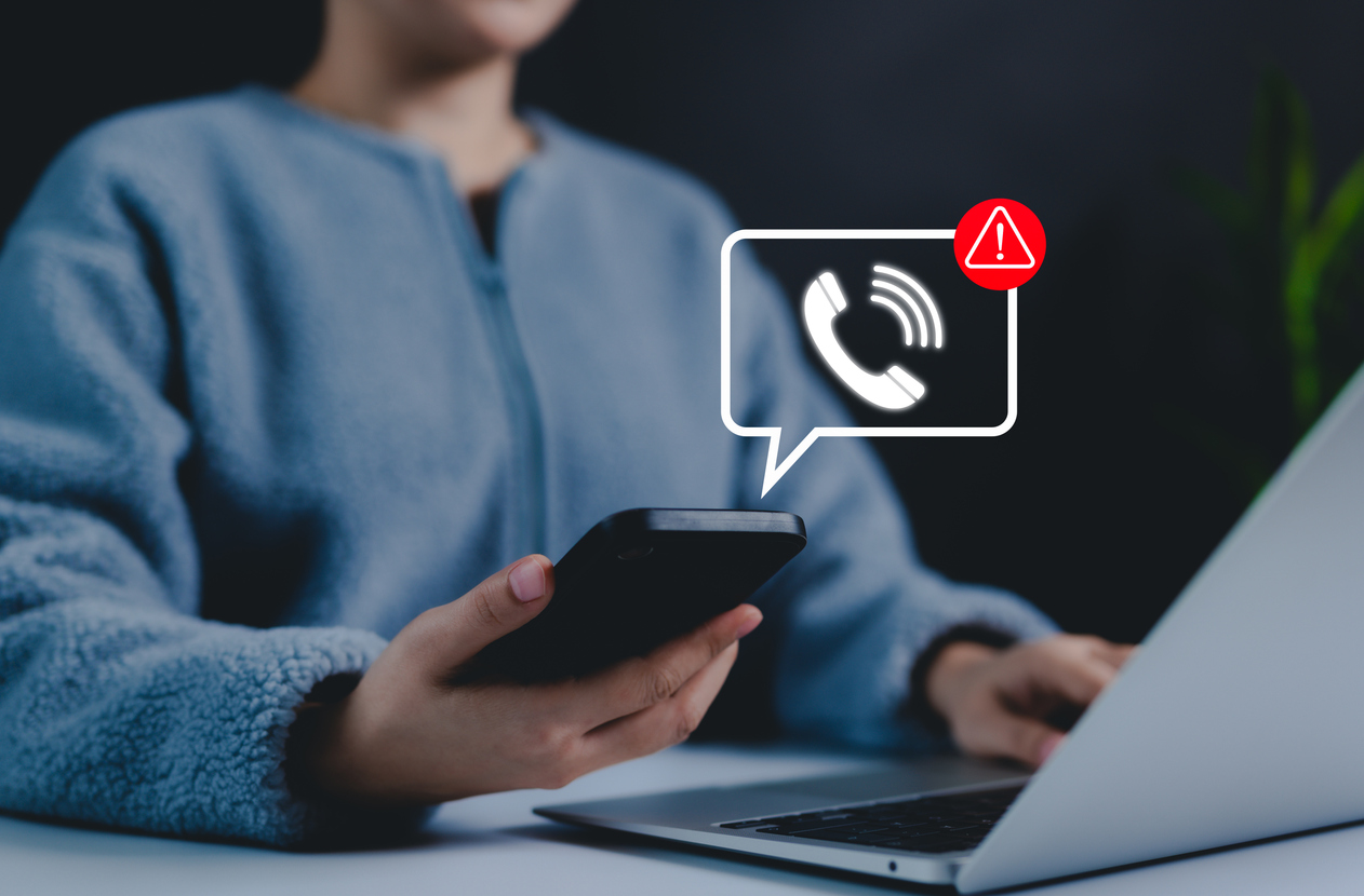 A person holding a smartphone with a digital scam warning notification.