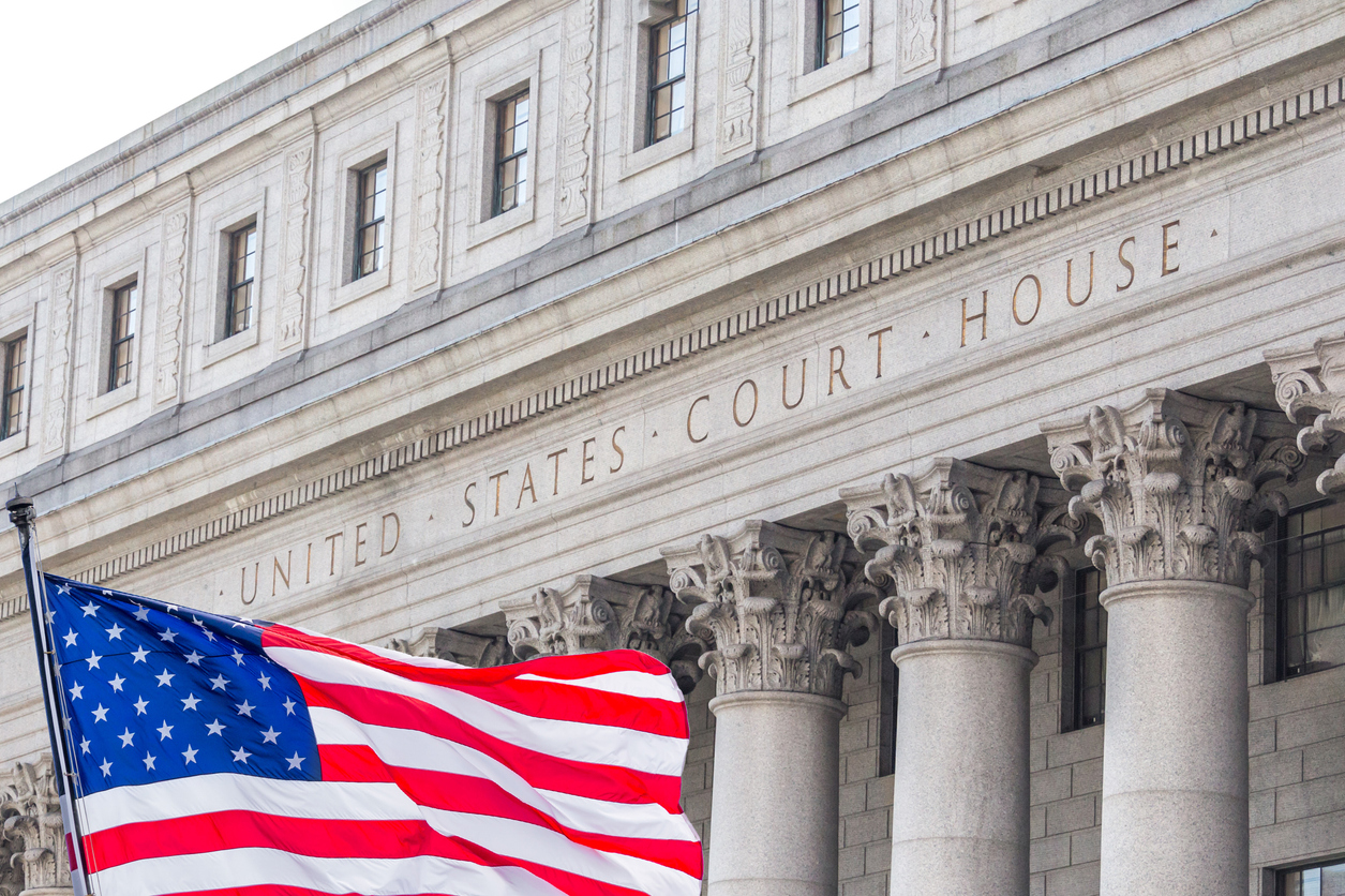 An American flag waving in the wind in front of a federal courthouse